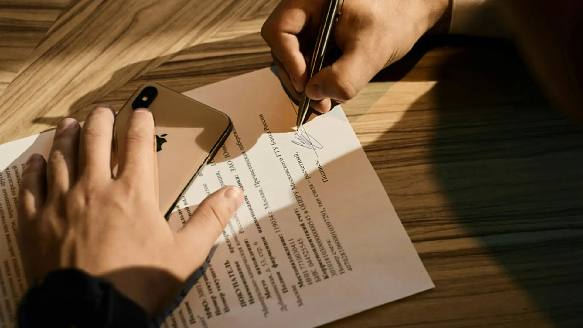A document being signed with a pen on a wooden desk