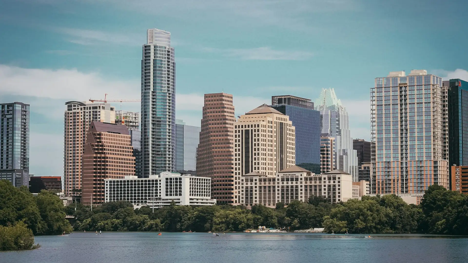 A downtown skyline beyond a calm lake on a clear day