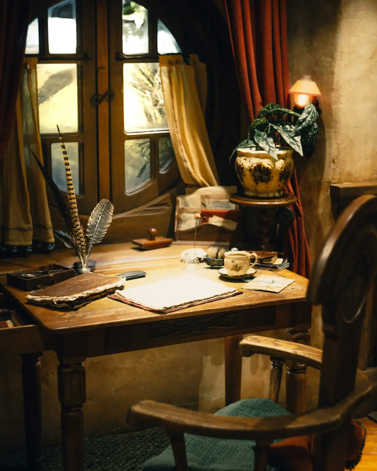 A writing desk by a window with a quill, ink and papers